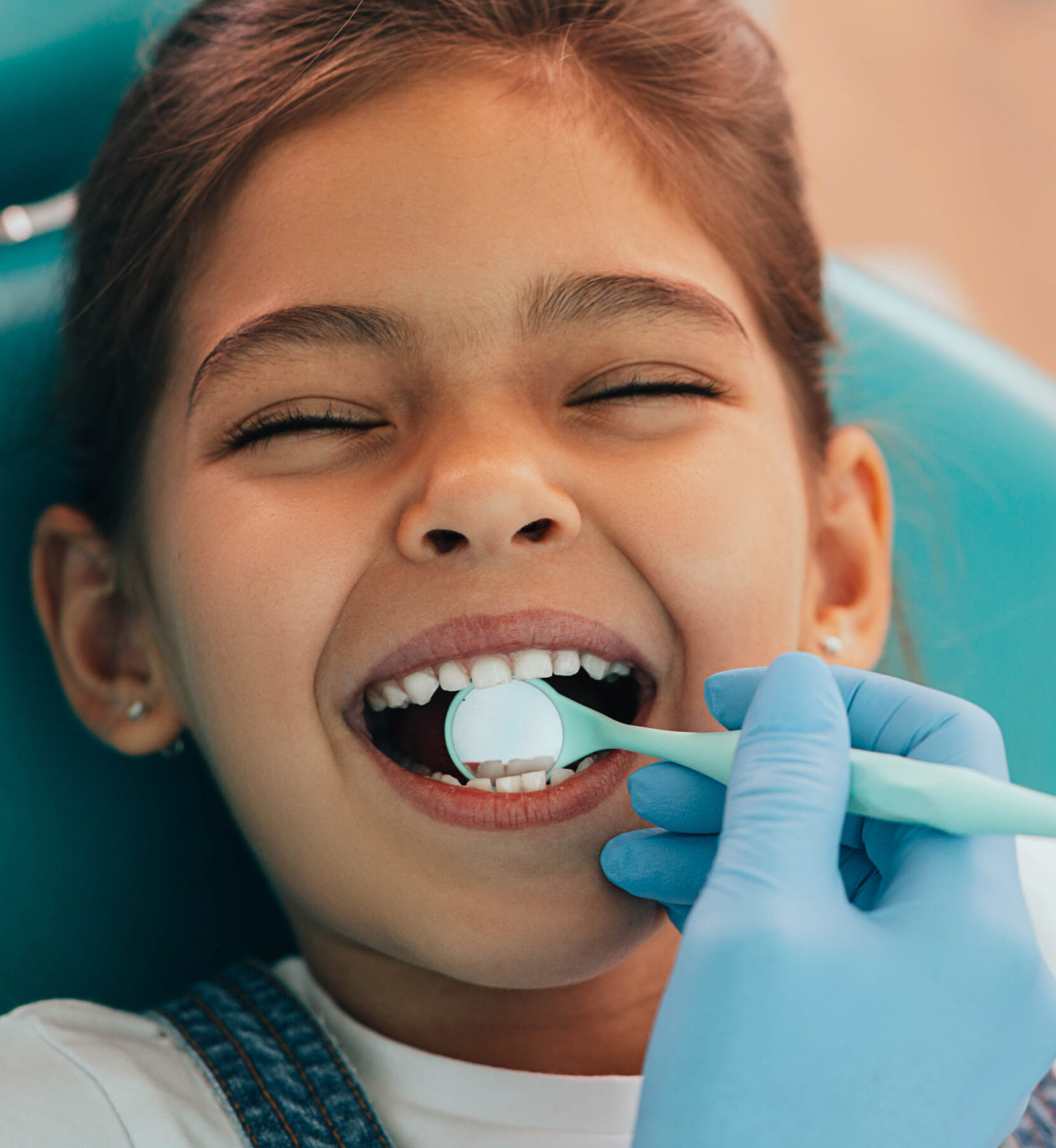 Cute little girl getting teeth exam at dental clinic