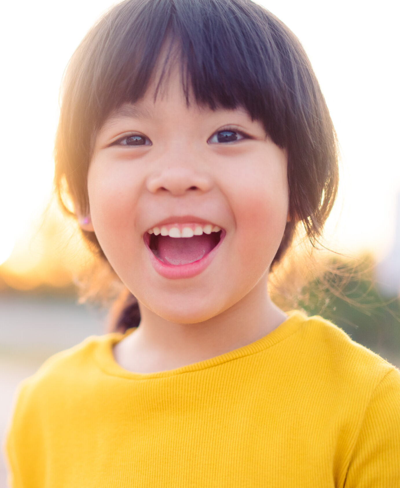 Happy Little asian girl child showing front teeth with big smile