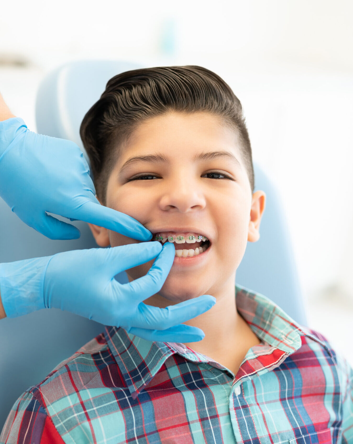 Female orthodontist examining cute boy wearing braces