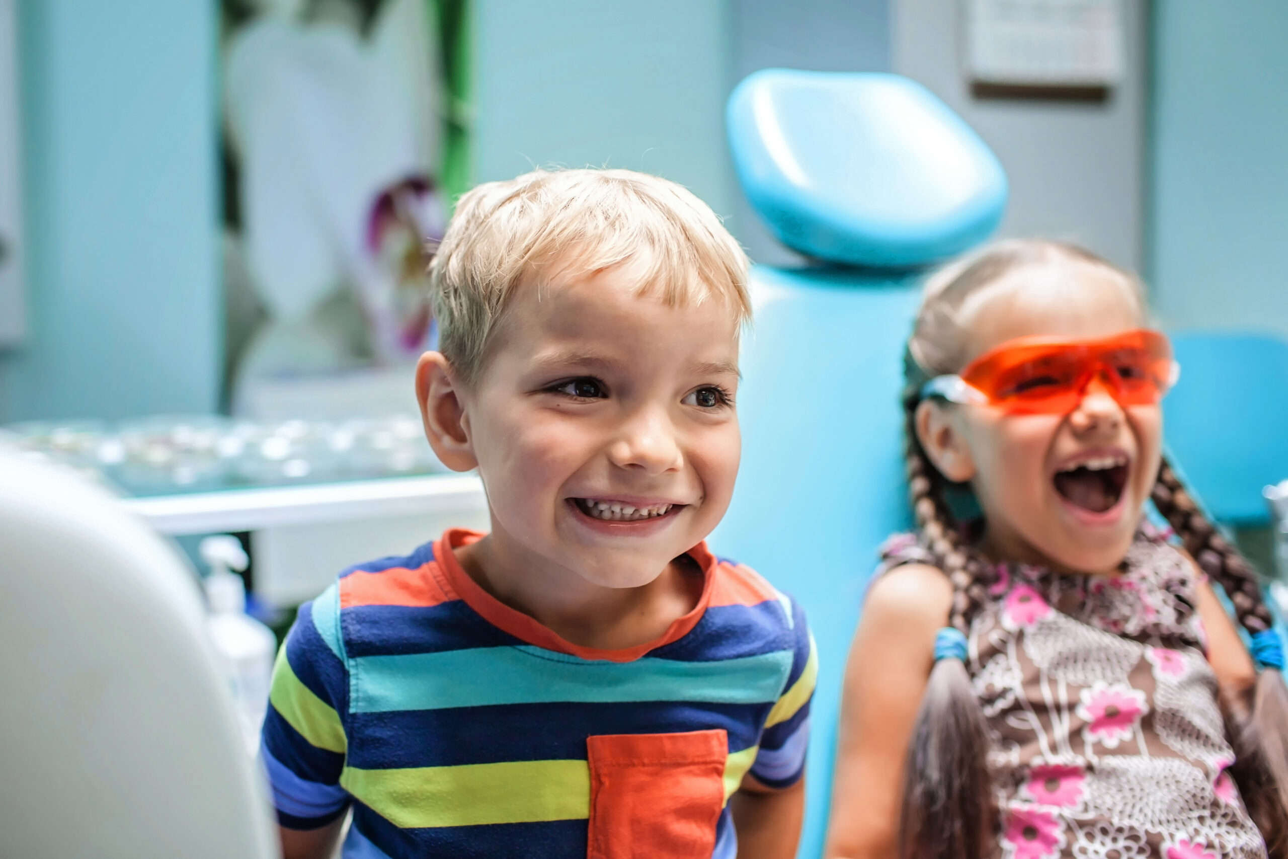 Two kids having fun and wearing medical eyeglasses during their visit to dentist office, the two are not scared. Healthy teeth and painless treatment, pediatric dentistry concept