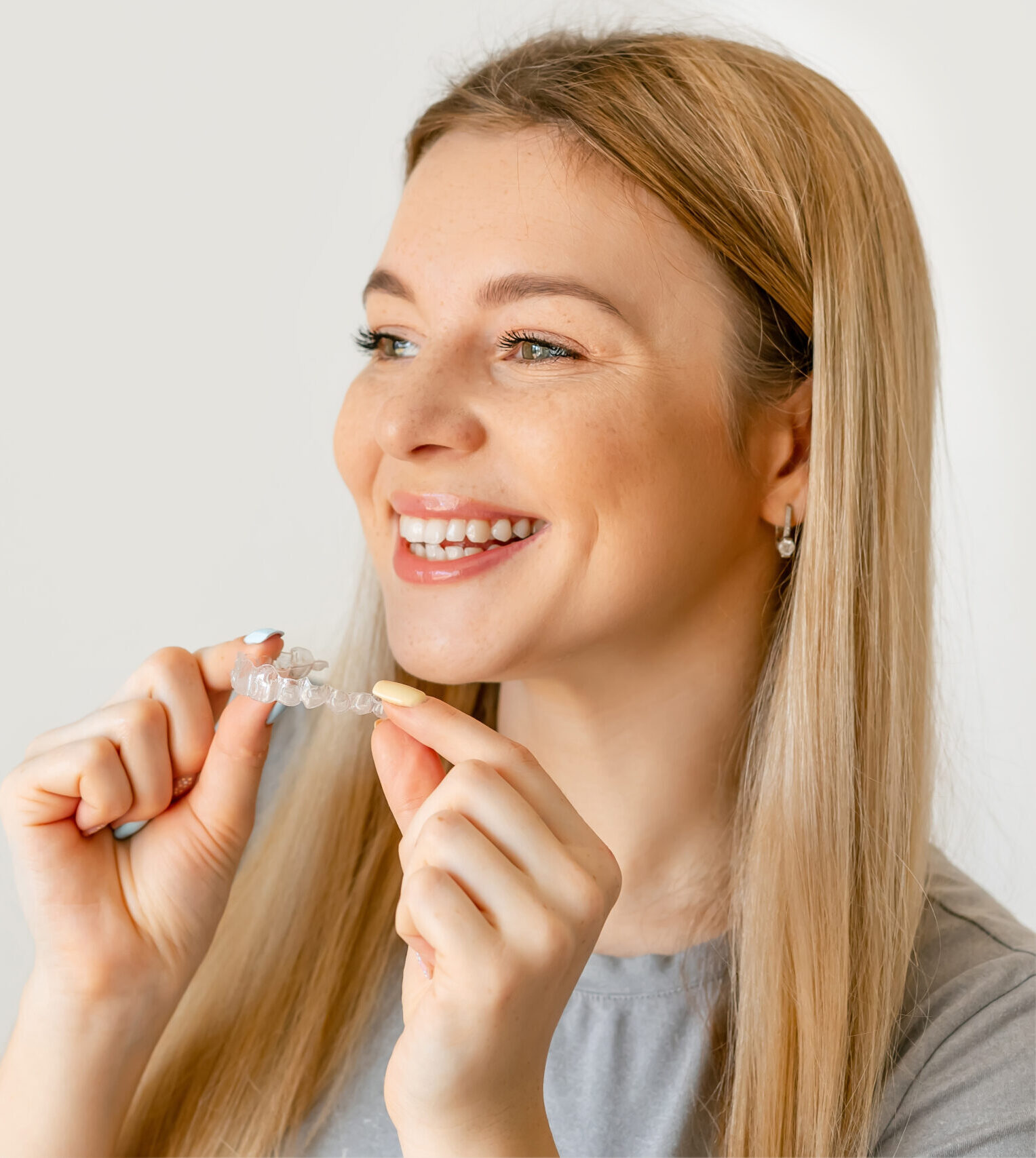 Orthodontics. Closeup Of Beautiful Happy Smiling Woman With White Smile, Straight Teeth Holding Whitening Tray, Invisible Braces, Teeth Trainer. Dental Treatment. Copy space