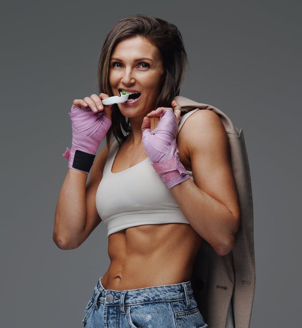 Joyful female sportsperson with jacket and mouth guard in studio