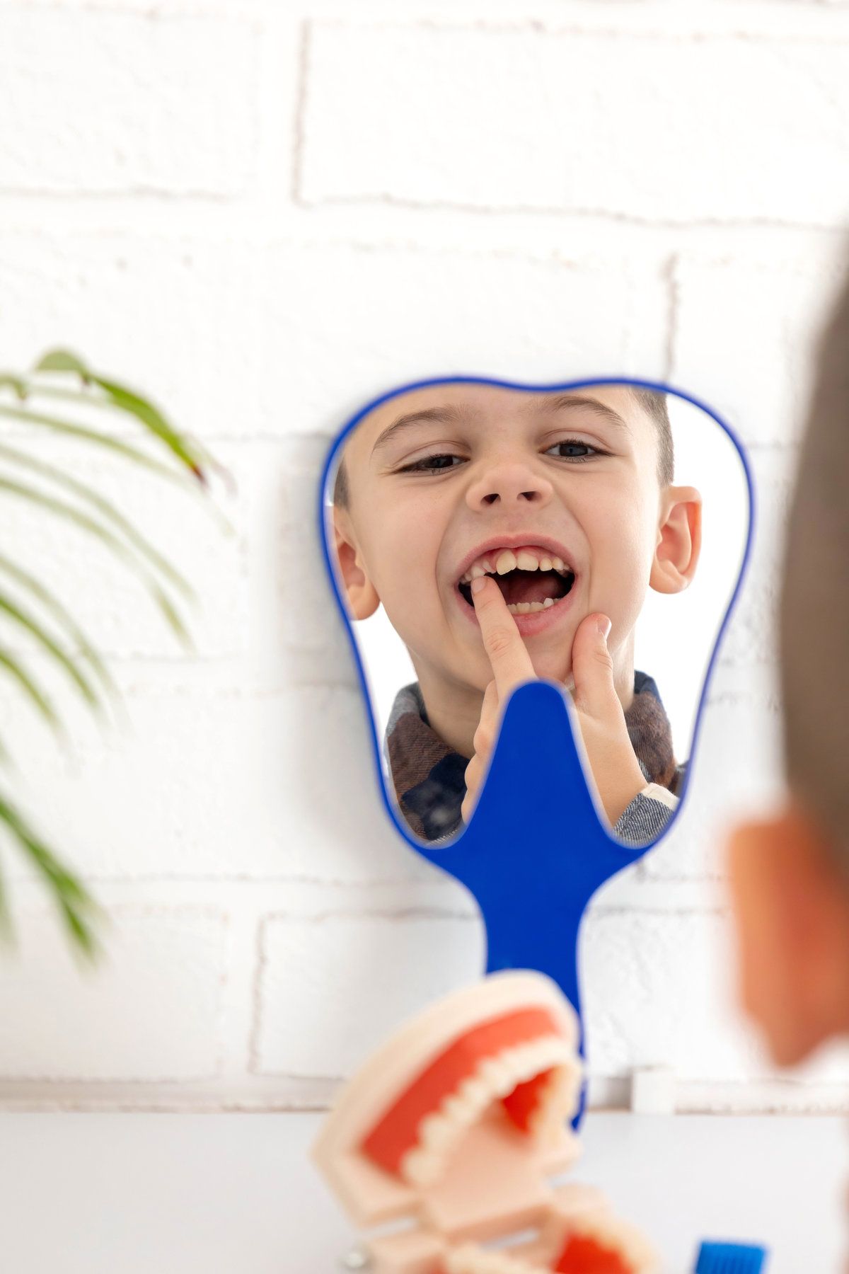 Little boy looking in the mirror at his loose primary tooth