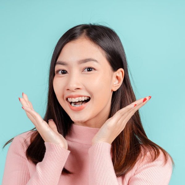 Dental braces of young asian woman wearing retainer braces glad emotion with white teeth increase confidence for healthy on blue background isolated, Happiness teenager smiling facial expression.